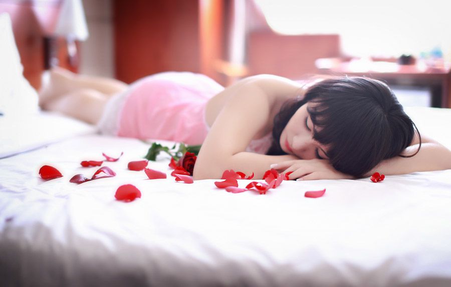 バラの花びらとともに寝る女性