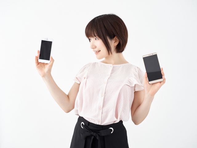 iPhoneとAndroidを片手ずつに持つ女の子