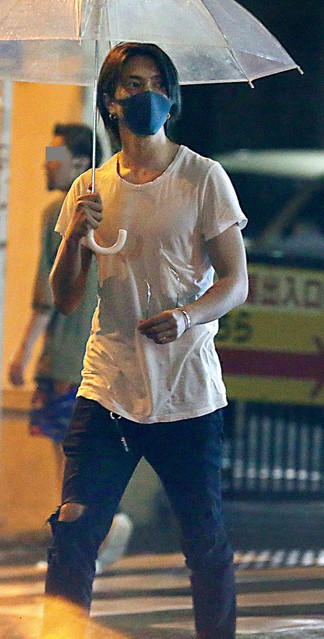 白Tシャツにジーンズで傘をさした男性