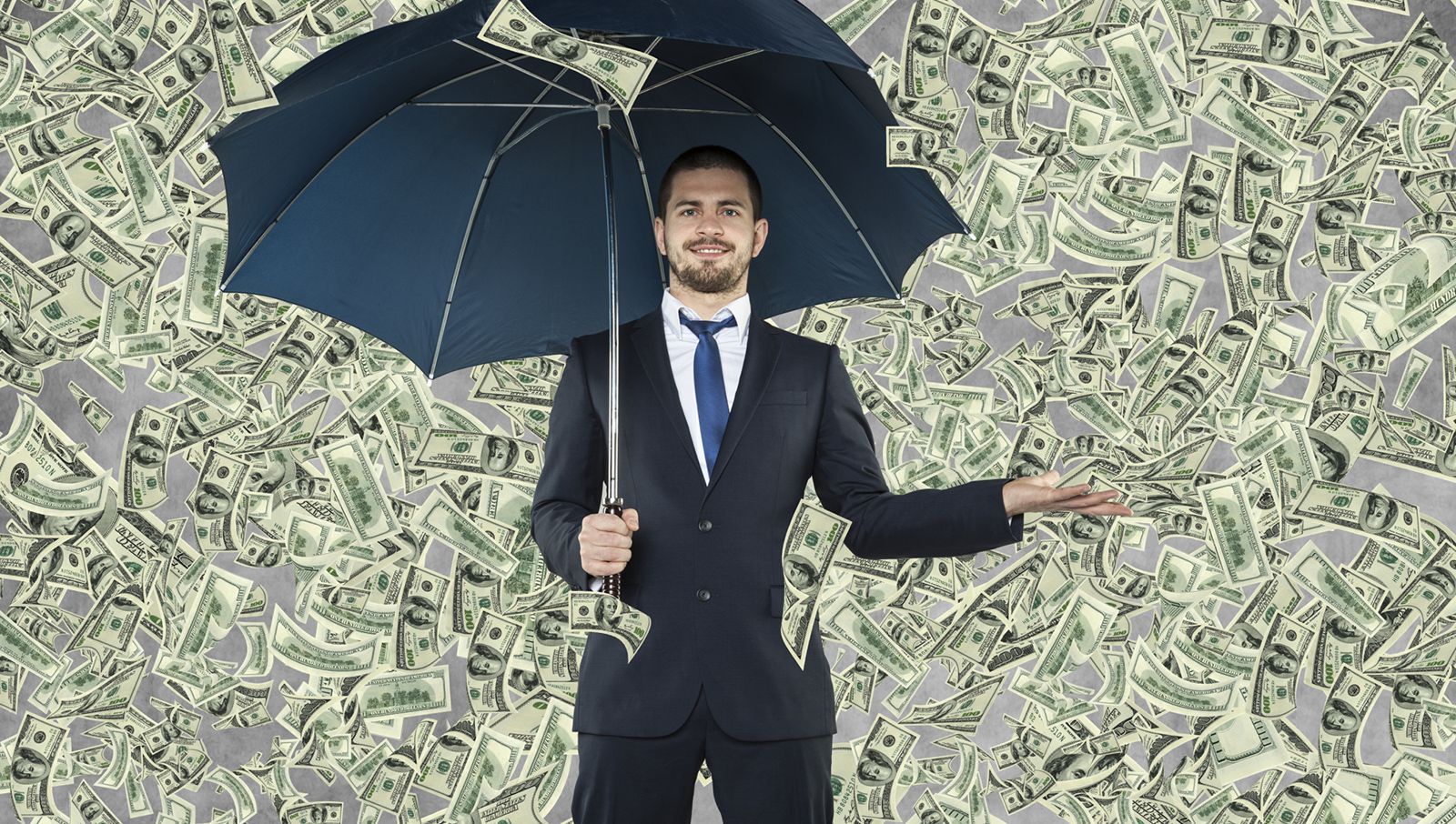 空から大量に降るお金の中で傘をさす男性